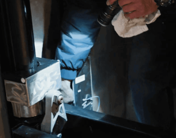 A Stanley Elevator Technician uses a flashlight to check the electrical system of an elevator during an elevator inspection service call.